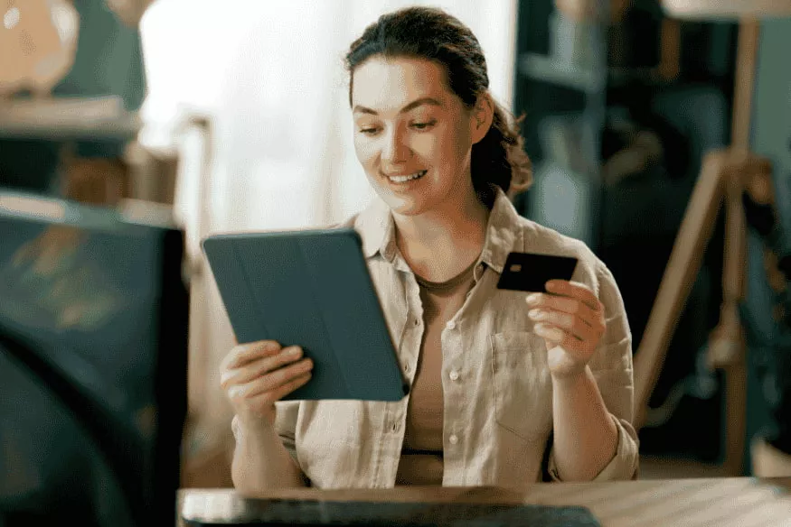 Donna che fa shopping online con carta di pagamento e tablet utilizzando il servizio Buy Now Pay Later per rateizzare gli acquisti.