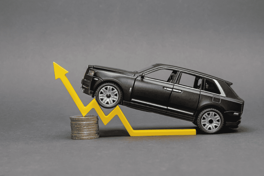 Miniatura de SUV preto sobre gráfico de alta com moedas, simbolizando aumento nos preços dos carros importados