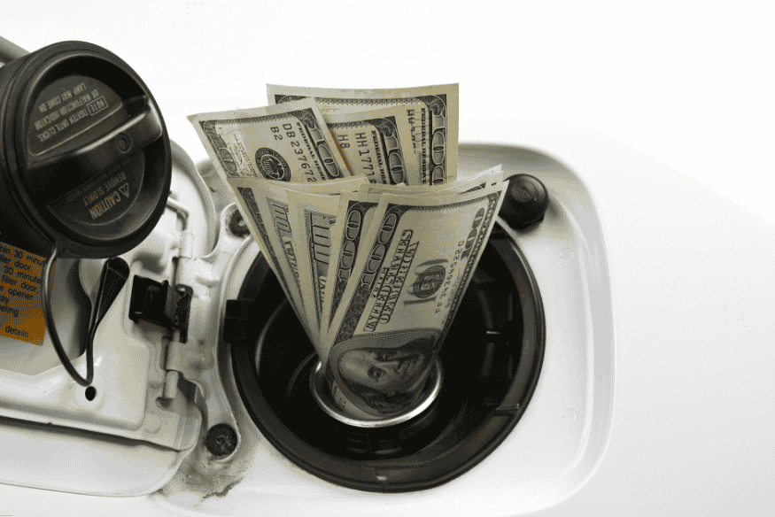 Notas de dólar dentro do tanque de combustível de um carro, representando o custo de abastecimento