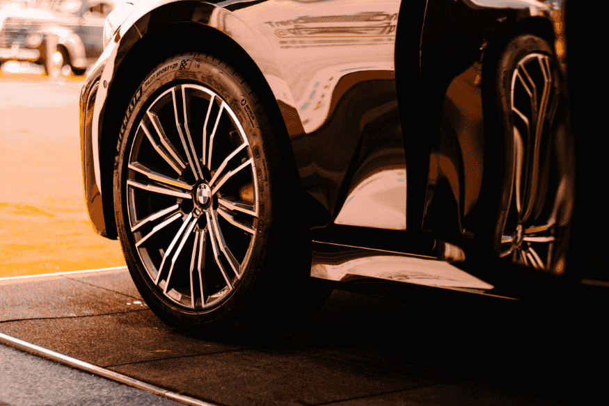 Roda esportiva com pneu de perfil baixo em carro de alto desempenho em ambiente urbano.