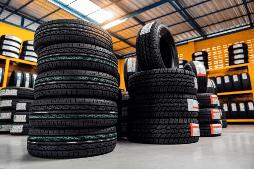 Estoque de pneus de diferentes modelos e tamanhos em loja automotiva.