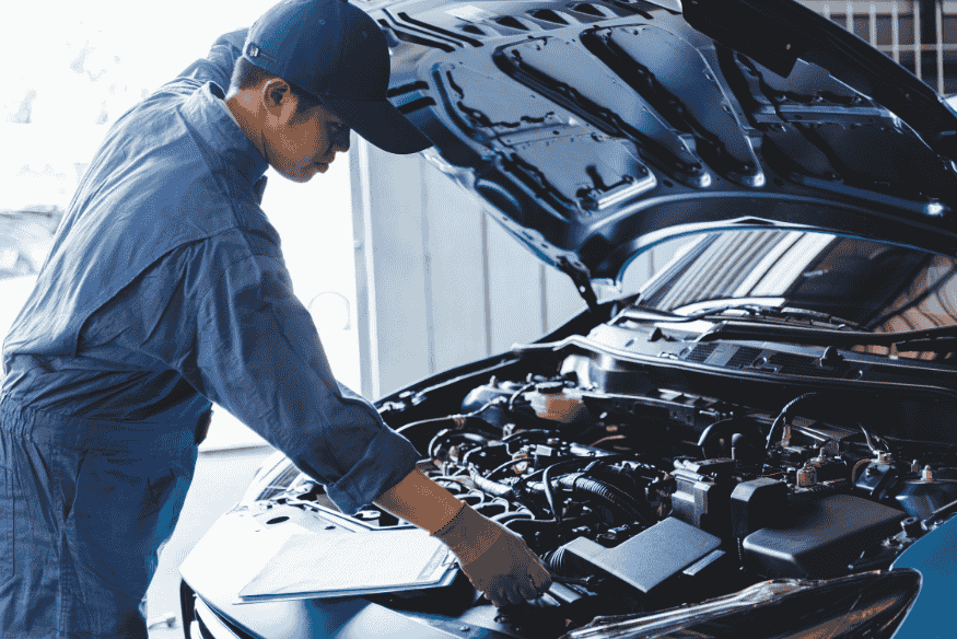 Mecânico inspecionando minuciosamente o motor de um veículo com o capô aberto.