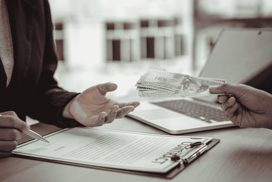 Persona che consegna banconote a un’altra durante la firma di un contratto commerciale.