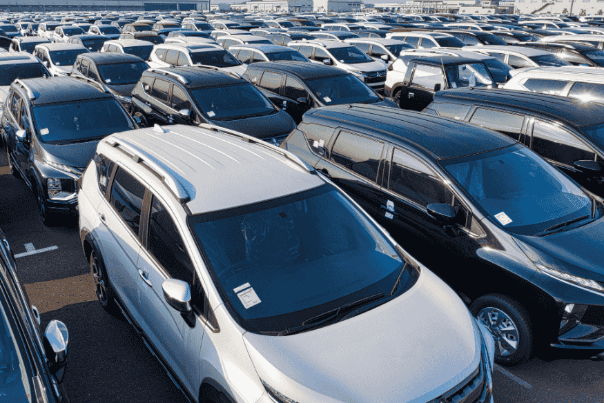 Estacionamento repleto de veículos SUV recém-produzidos, alinhados para distribuição.