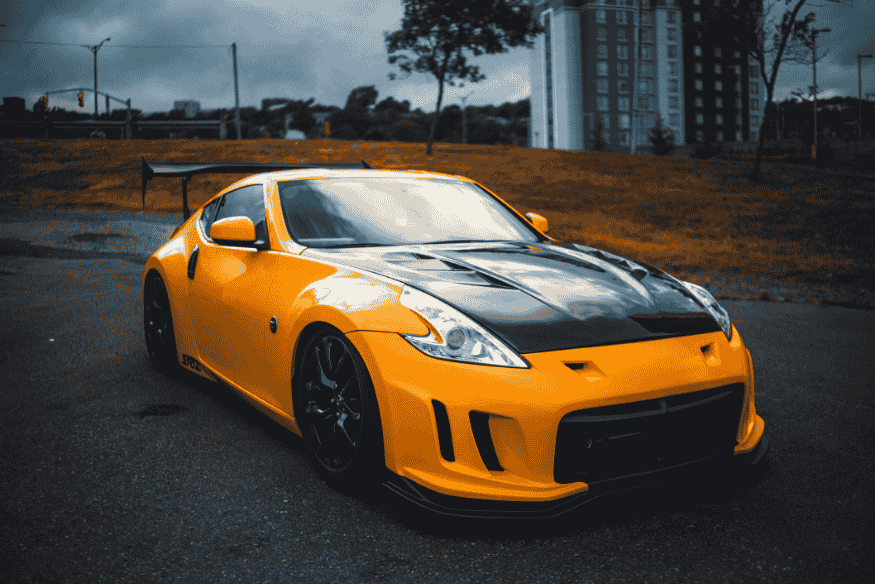 Carro esportivo amarelo com detalhes em preto estacionado ao ar livre, destacando visual agressivo