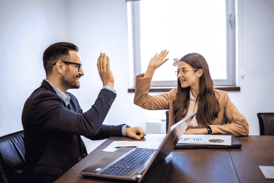 Due professionisti in ufficio che si danno il cinque dopo aver concluso con successo un accordo di recupero crediti.