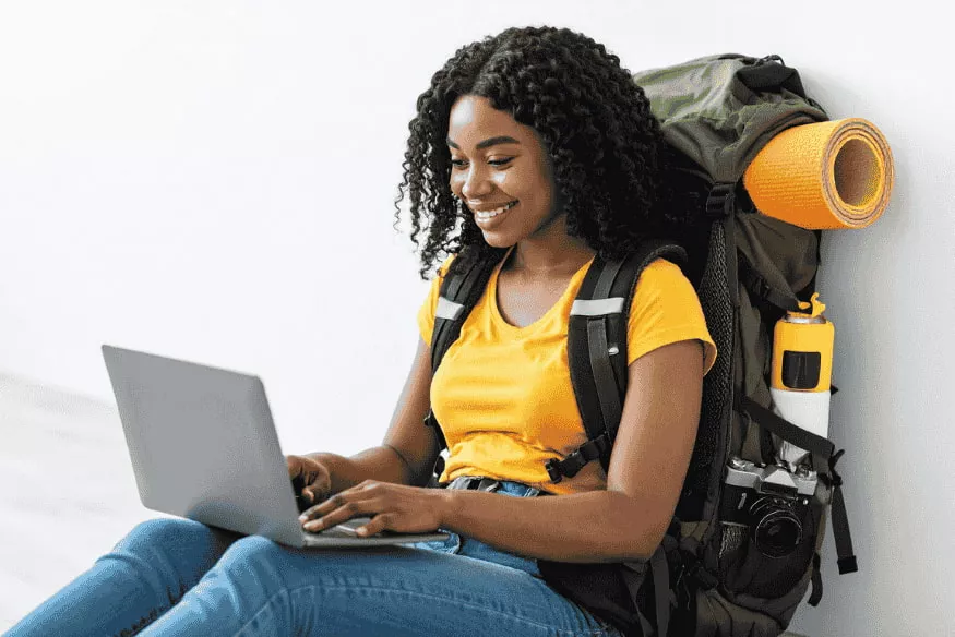 Viaggiatrice con zaino da backpacker che controlla online le proprie finanze durante un soggiorno all’estero