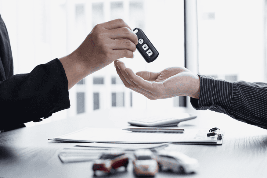 Pessoa entregando chave de carro a outra em ambiente corporativo, simbolizando um contrato ou financiamento