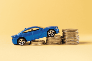 Miniatura de carro azul subindo em pilhas de moedas, representando o aumento de custos com o IPVA