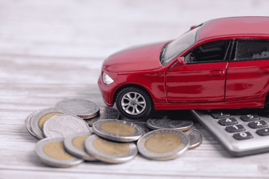 Carro de brinquedo sobre moedas e calculadora, simbolizando o impacto do IPVA no orçamento do veículo