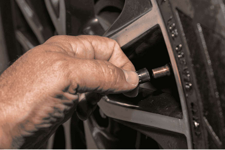 Mão ajustando válvula de pneu para verificação da pressão correta