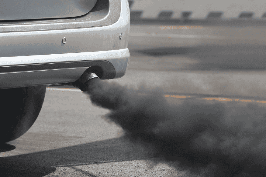 Emissão de fumaça preta saindo do escapamento de um carro em movimento
